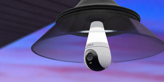 Lorex 2K Wi-Fi lightbulb security camera mounted in a modern black outdoor fixture, combining smart lighting and surveillance for enhanced home security at dusk.