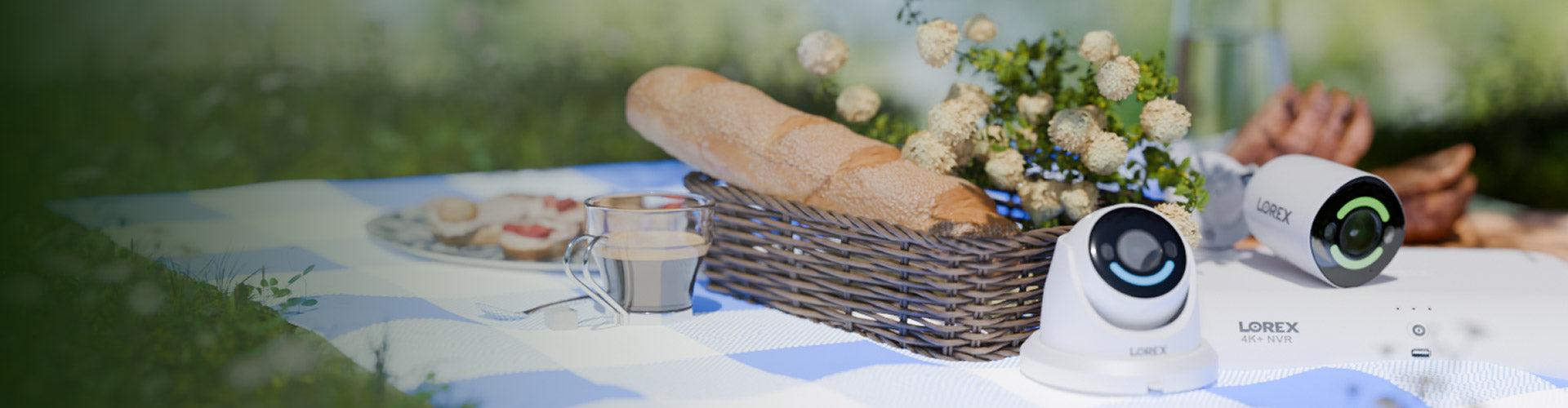 Lorex security cameras and 4K NVR on an outdoor picnic table with bread, flowers, and a spring setting in the background