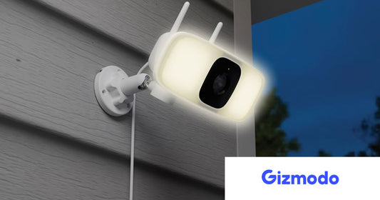 Lorex Connect 2K Floodlight Security Camera mounted outdoors on home siding at dusk, with built-in LED floodlight illuminated and dual antennas visible, highlighting AI-powered outdoor protection.