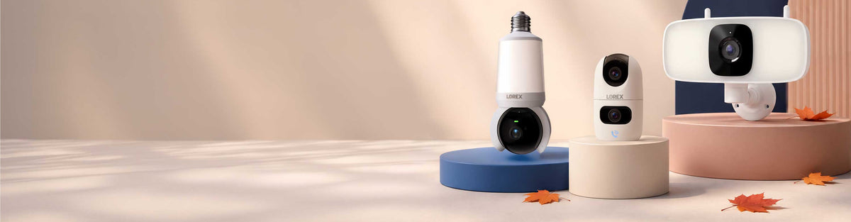 Lorex indoor Wi-Fi cameras displayed on seasonal fall-themed pedestals with autumn leaves.